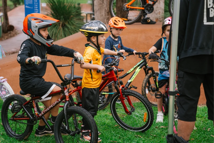 Children on bmx bikes with helmets on listening to instructor. 